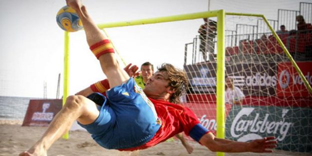 chico rematando al fútbol en la playa