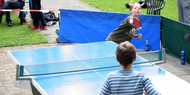 Niños jugando al ping pong en el jardín